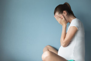 upset pregnant woman crying in her hands